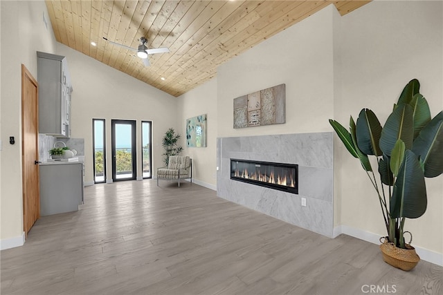 living room with wooden ceiling, high vaulted ceiling, a tile fireplace, light hardwood / wood-style flooring, and ceiling fan