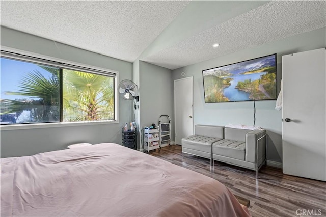 bedroom with a textured ceiling, wood finished floors, lofted ceiling, and baseboards