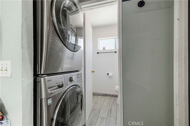 laundry room featuring stacked washer and clothes dryer and light hardwood / wood-style floors