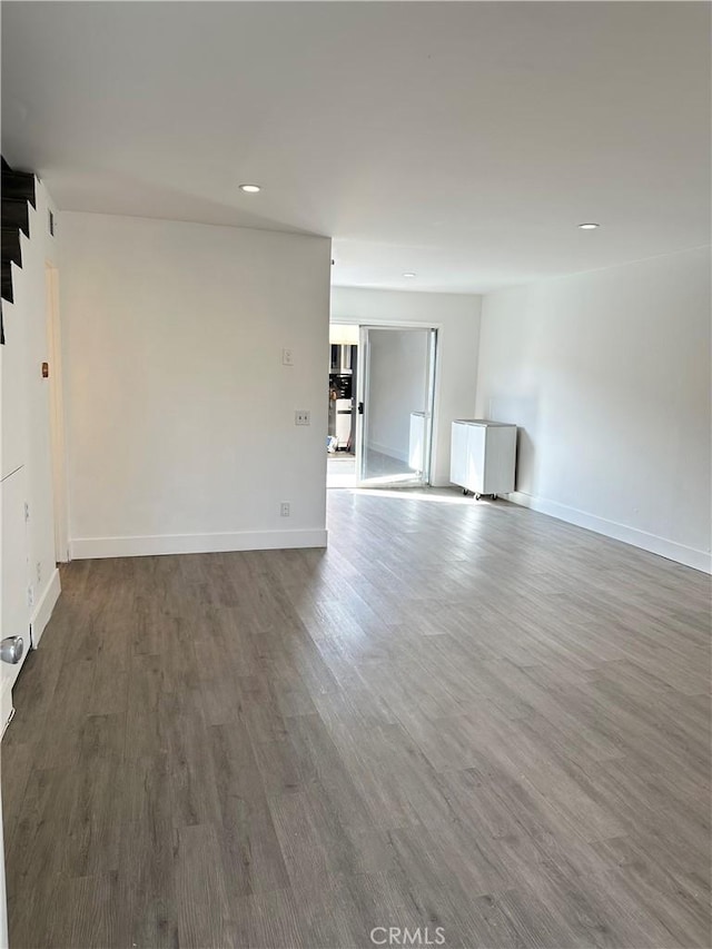 spare room with baseboards, wood finished floors, and recessed lighting