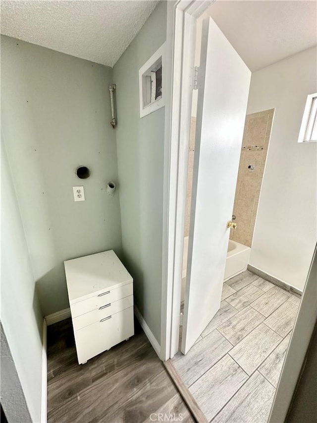 full bathroom with a textured ceiling, wood finished floors, shower / tub combination, and baseboards