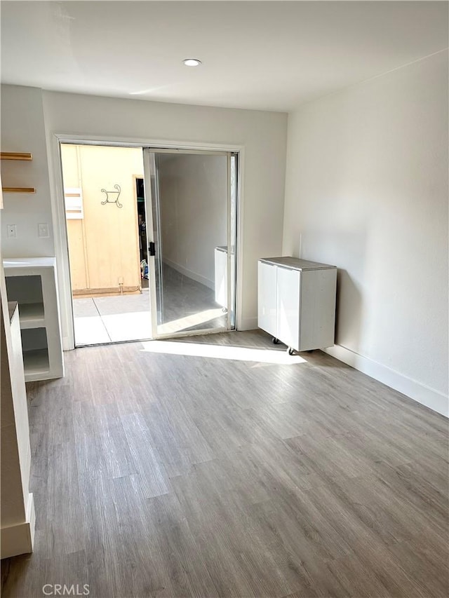 unfurnished room featuring recessed lighting, wood finished floors, and baseboards