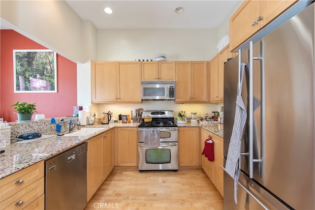 kitchen featuring stainless steel appliances, light stone countertops, light hardwood / wood-style floors, and light brown cabinetry