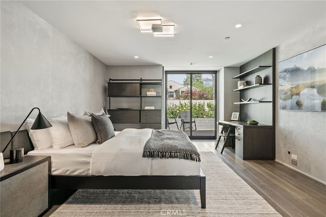 bedroom with access to exterior, hardwood / wood-style floors, and a wall of windows