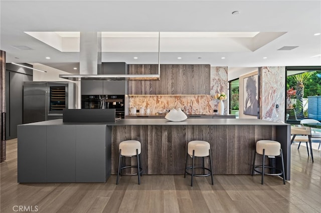 kitchen with a kitchen breakfast bar, a spacious island, a wall of windows, and light wood-type flooring