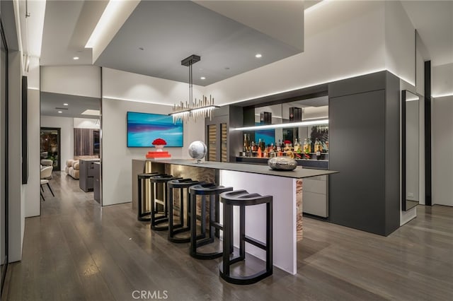 kitchen featuring kitchen peninsula, a towering ceiling, dark hardwood / wood-style flooring, pendant lighting, and a breakfast bar area