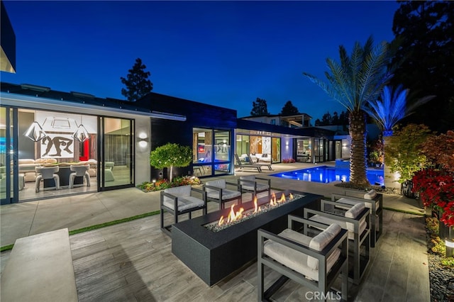 back house at night featuring a patio area and a fire pit