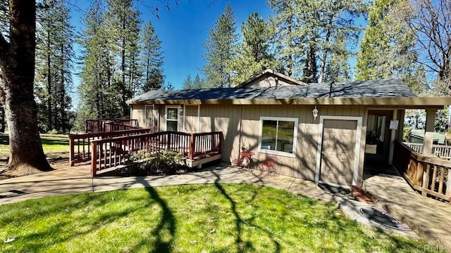 rear view of house featuring a wooden deck, a patio, and a lawn