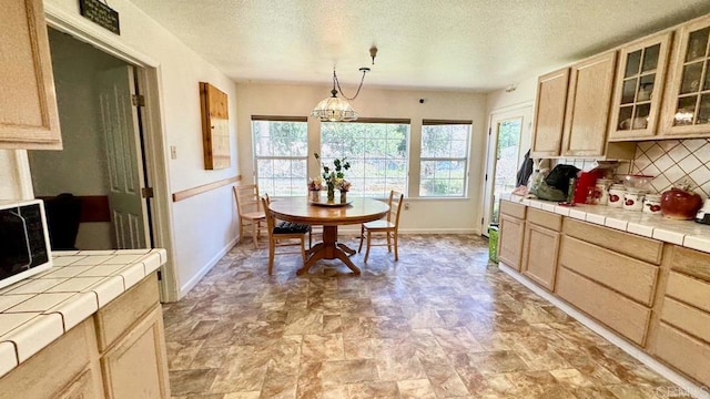 kitchen with decorative backsplash, tile countertops, pendant lighting, an inviting chandelier, and light brown cabinetry