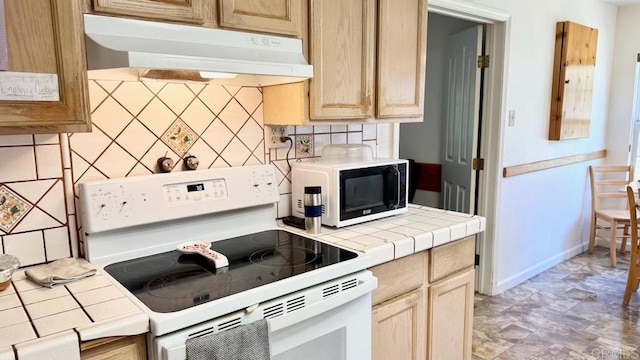 kitchen featuring backsplash, range, light brown cabinets, and tile counters