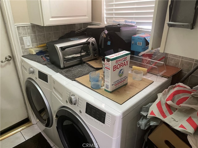 laundry room with cabinets, light tile patterned flooring, and washing machine and clothes dryer