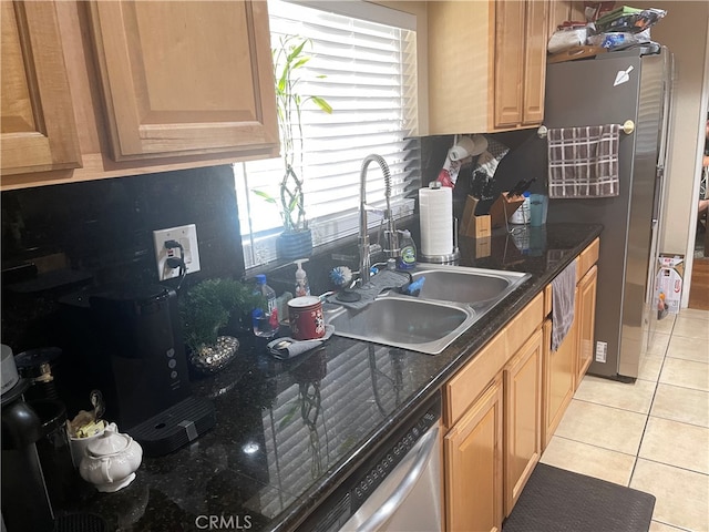 kitchen with sink, dark stone countertops, stainless steel appliances, and light tile patterned floors