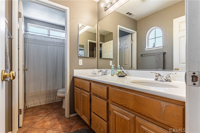 bathroom with vanity, tile patterned flooring, toilet, and walk in shower