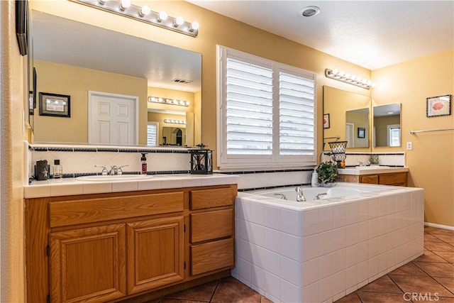 bathroom featuring tile patterned floors, tiled tub, and vanity