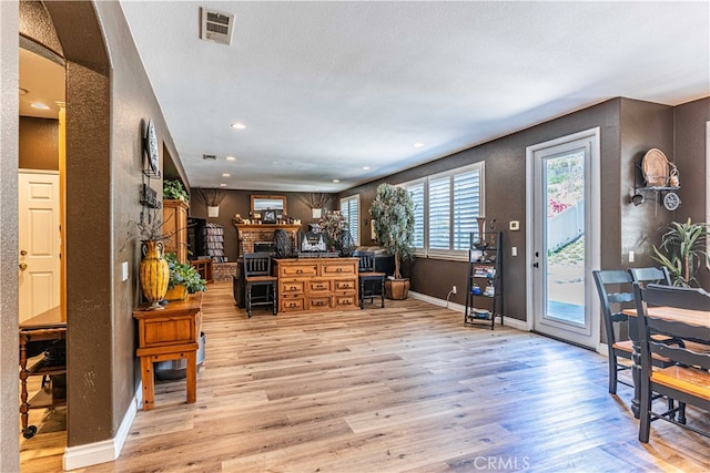 entrance foyer with a textured ceiling, a fireplace, and light hardwood / wood-style floors