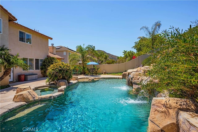 view of pool with a patio, an in ground hot tub, and pool water feature