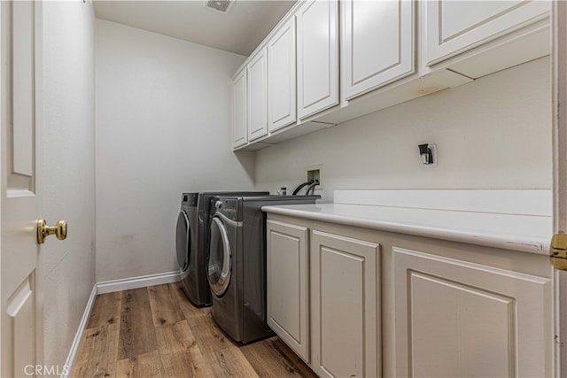 washroom featuring cabinets, light hardwood / wood-style flooring, and washer and dryer