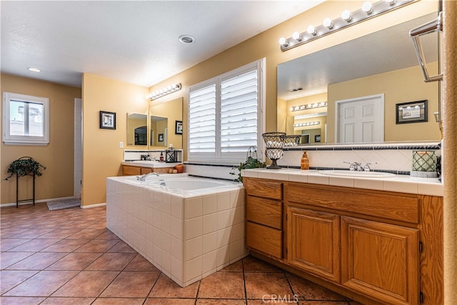 bathroom with tile patterned floors, tiled tub, and vanity