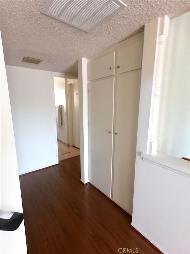 hallway featuring dark hardwood / wood-style flooring and a textured ceiling