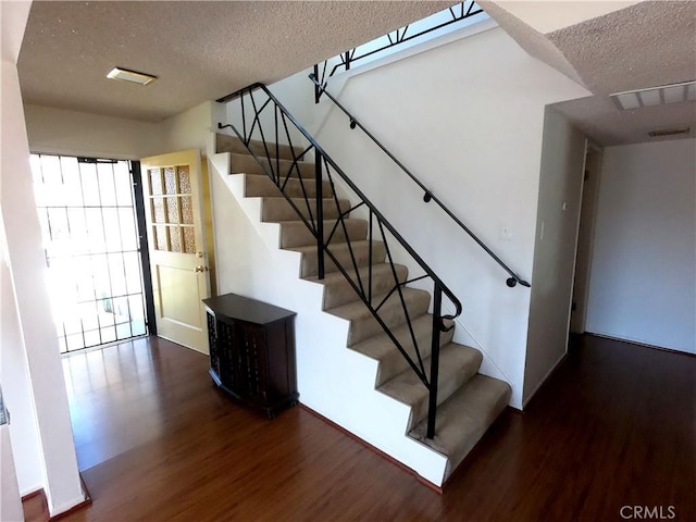 staircase with wood-type flooring and a textured ceiling