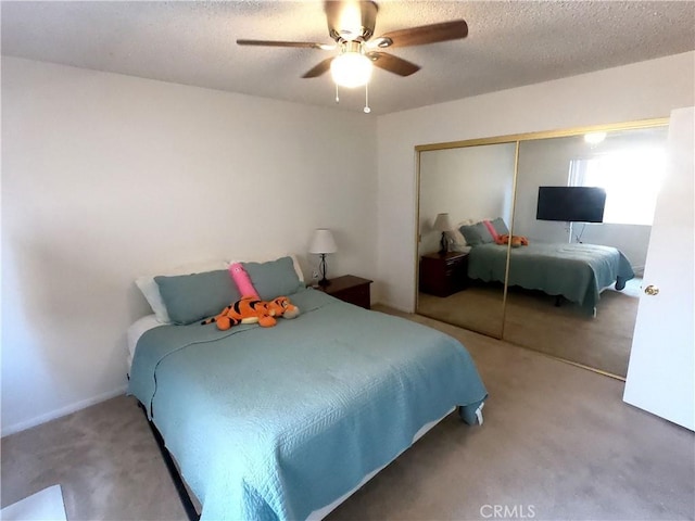 carpeted bedroom featuring ceiling fan, a closet, and a textured ceiling