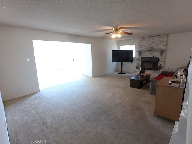 living room featuring light carpet, a textured ceiling, a wood stove, and ceiling fan