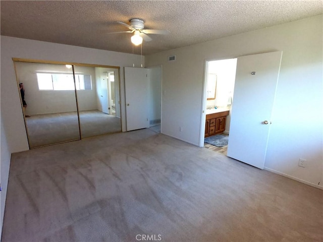 unfurnished bedroom featuring ceiling fan, a closet, light carpet, and a textured ceiling