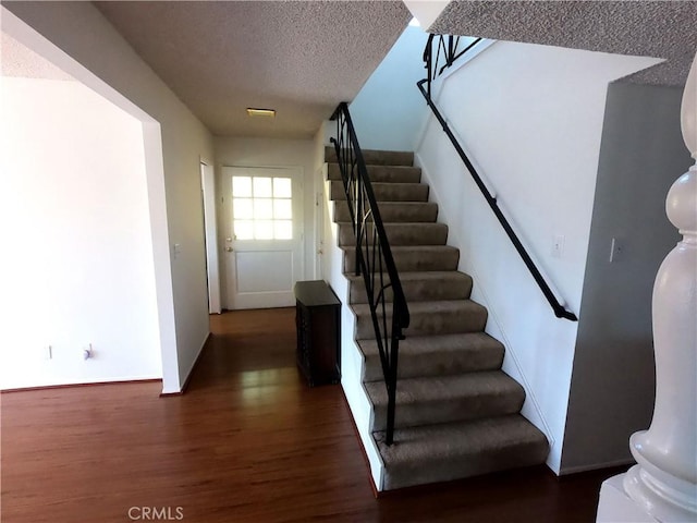 stairs featuring wood-type flooring and a textured ceiling