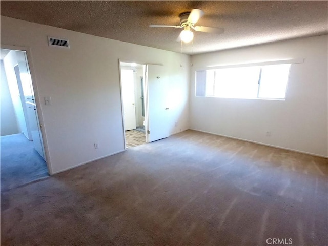 spare room with a textured ceiling, light colored carpet, and ceiling fan