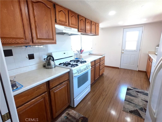 kitchen with decorative backsplash, gas range gas stove, and hardwood / wood-style floors