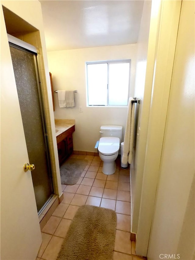 bathroom with toilet, vanity, tile patterned floors, and a shower with shower door