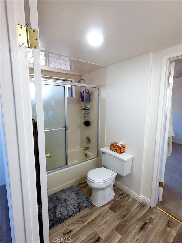 bathroom with shower / bath combination with glass door, wood-type flooring, and toilet