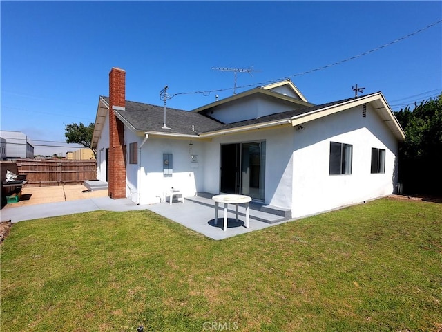 rear view of property featuring a lawn, a patio area, and electric panel