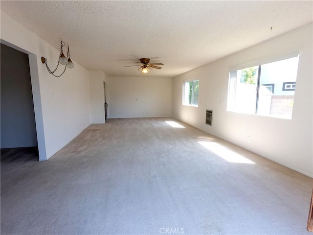 spare room featuring ceiling fan, carpet floors, a textured ceiling, and heating unit