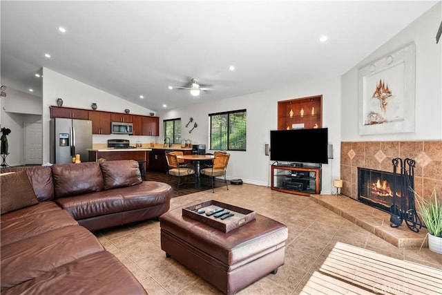 living room with a tile fireplace, sink, vaulted ceiling, ceiling fan, and light tile patterned floors