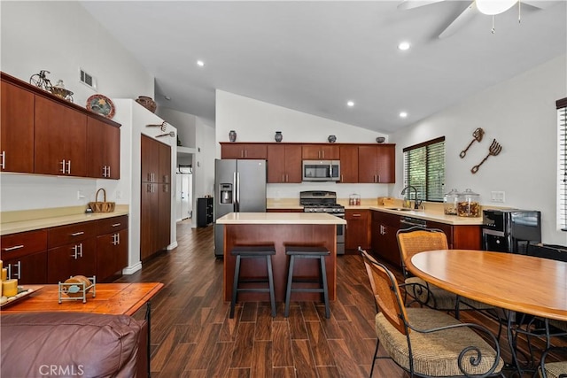 kitchen with dark wood-type flooring, a kitchen island, stainless steel appliances, and vaulted ceiling