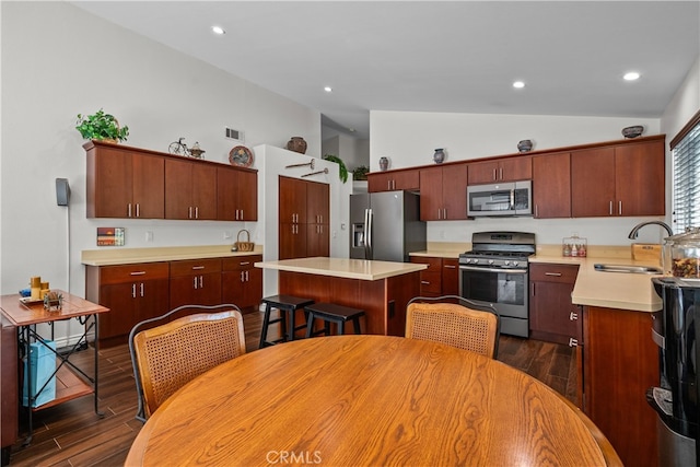 kitchen with stainless steel appliances, vaulted ceiling, sink, a center island, and dark hardwood / wood-style floors