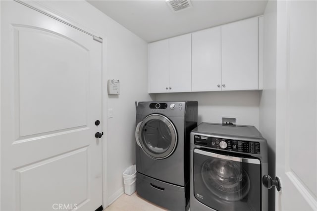 laundry room with separate washer and dryer and cabinets