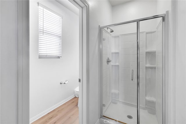 bathroom featuring wood-type flooring, a shower with door, and toilet