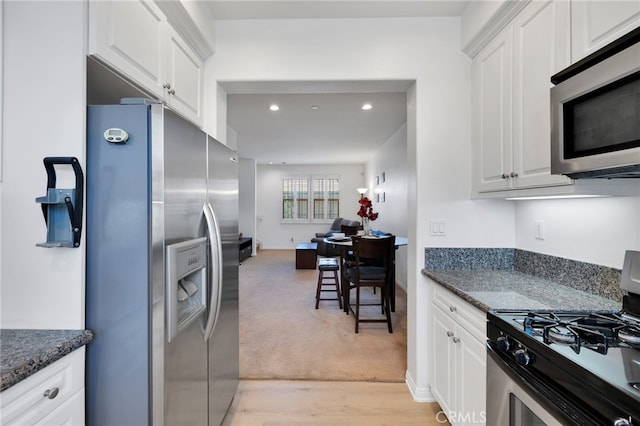 kitchen featuring light hardwood / wood-style flooring, stainless steel appliances, white cabinets, and dark stone countertops