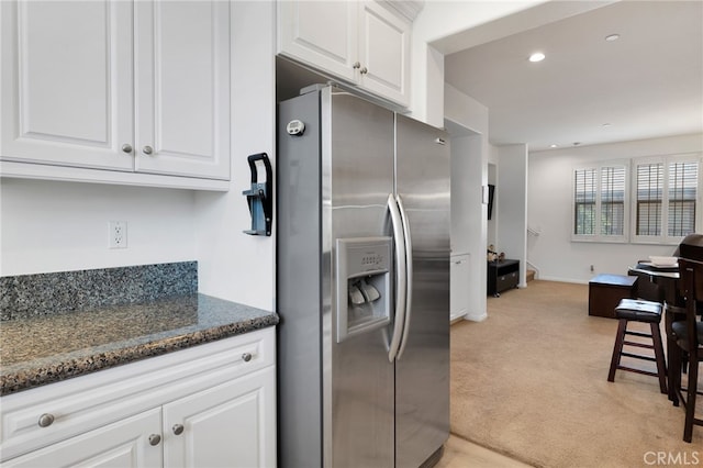 kitchen featuring dark stone countertops, stainless steel fridge, light carpet, and white cabinetry