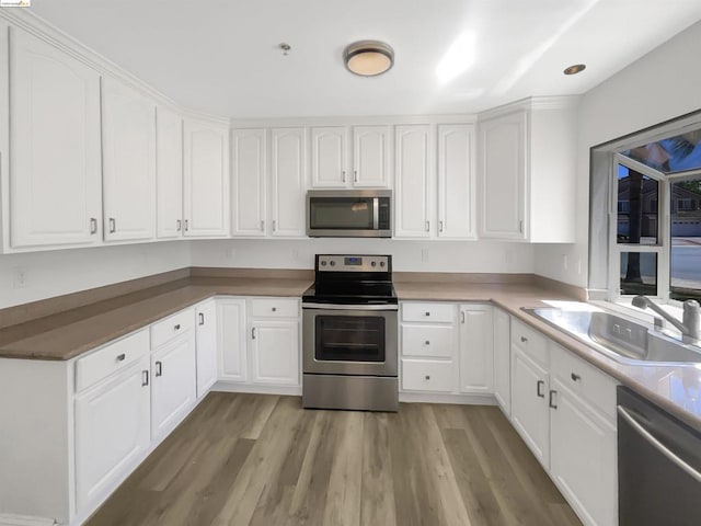 kitchen with white cabinetry, sink, light hardwood / wood-style floors, and appliances with stainless steel finishes