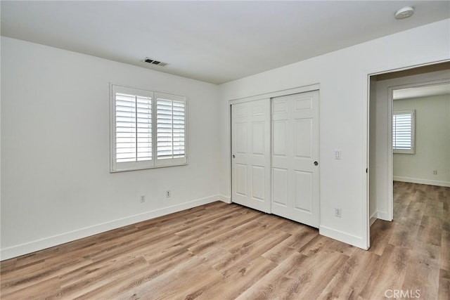 unfurnished bedroom with light hardwood / wood-style flooring and multiple windows