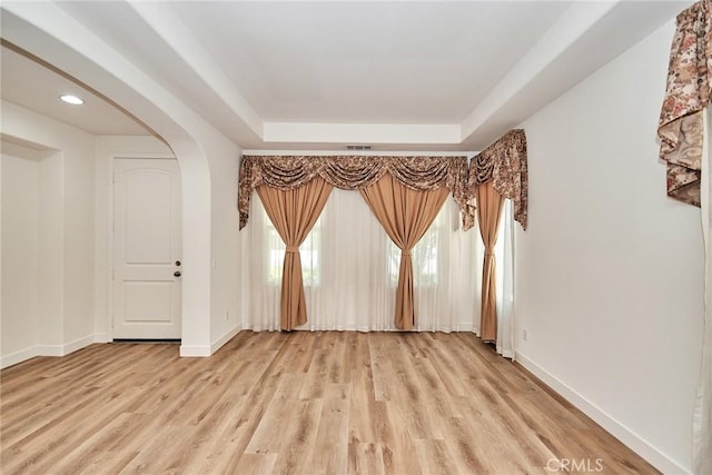 unfurnished room featuring a raised ceiling and light wood-type flooring