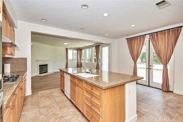 kitchen featuring french doors, white dishwasher, a kitchen island with sink, and a healthy amount of sunlight