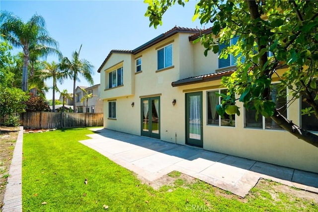 rear view of property featuring a yard, a patio, and french doors