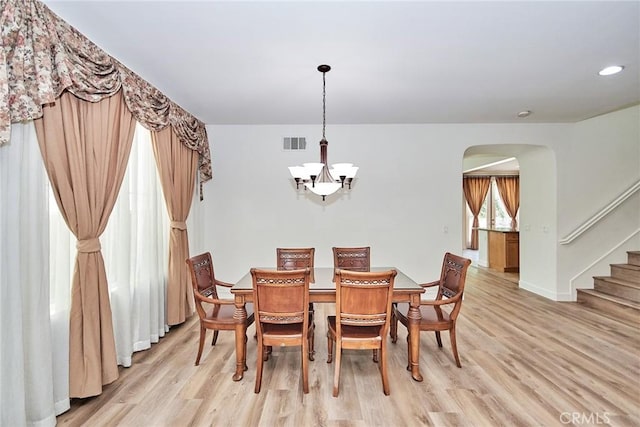 dining room with light wood-type flooring and an inviting chandelier