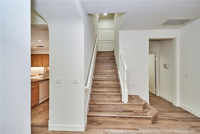 stairway featuring sink and hardwood / wood-style flooring