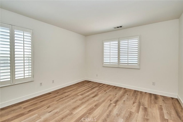 empty room with light hardwood / wood-style flooring and a wealth of natural light