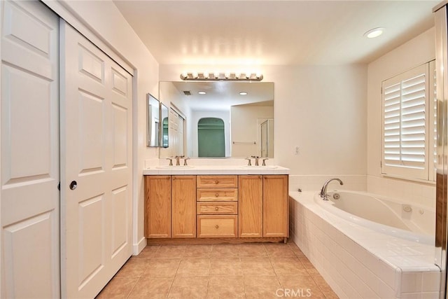 bathroom with tile patterned floors, vanity, and a relaxing tiled tub